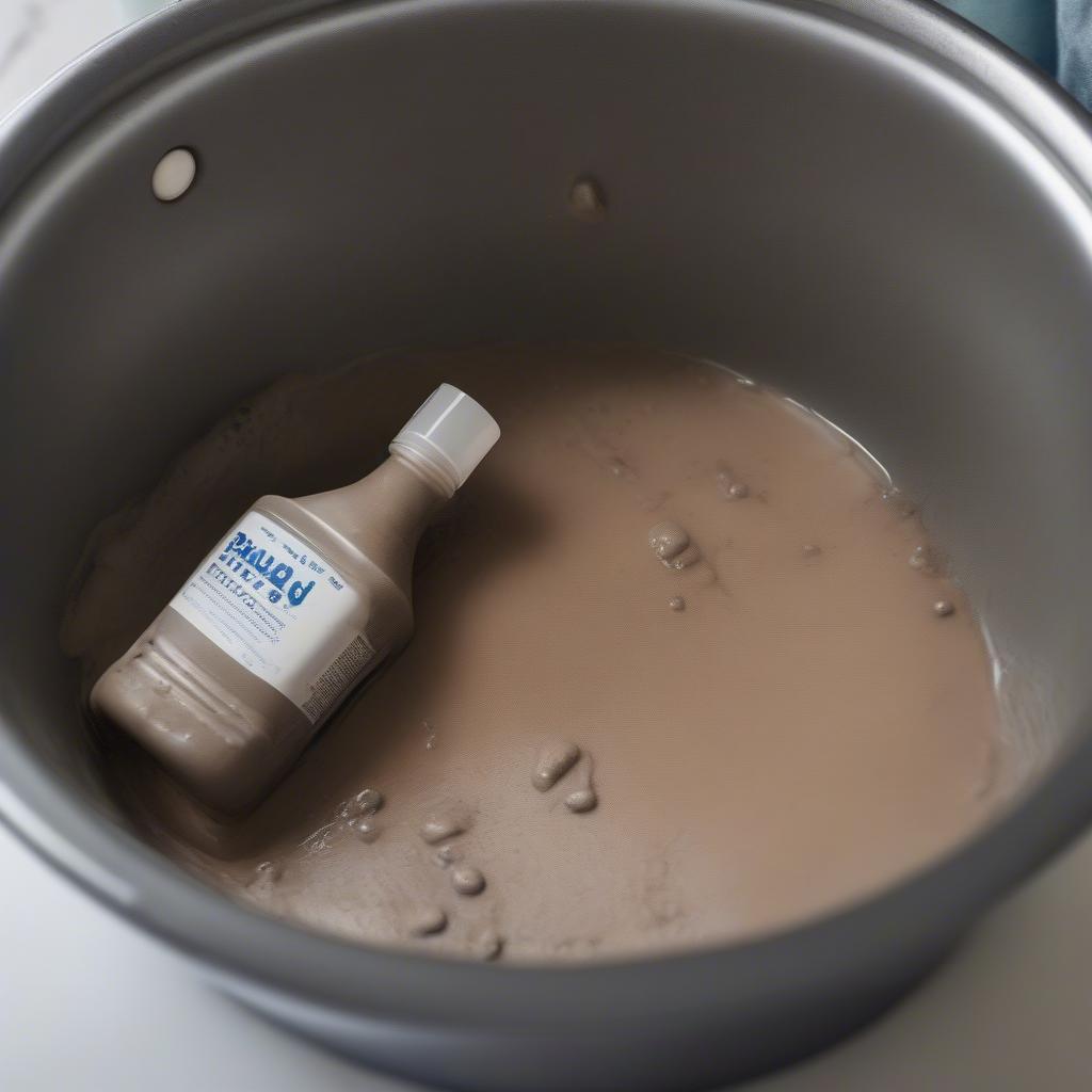 Step-by-step guide to cleaning mud-stained denim: A pair of jeans soaking in a basin, alongside cleaning supplies like detergent and a brush.