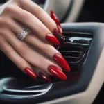 Woman with sexy red nails on steering wheel