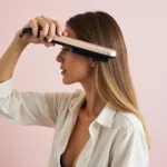 Woman using the amika mini straightening brush