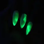 Glow in the dark black nail polish on nails, showcasing the luminescent effect in a darkened room.